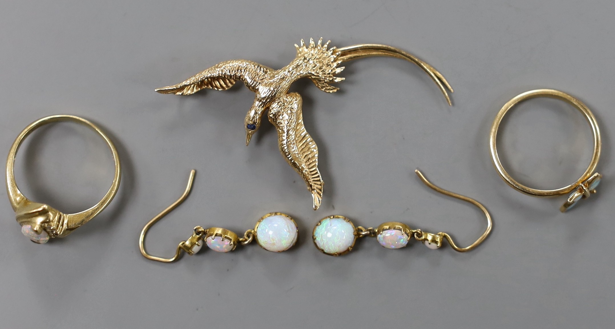 A 14k and gem set 'bird in flight' brooch, 50mm, gross weight 4.1 grams, a 9k and white opal ring, pair of yellow metal and white opal drop earrings and a yellow metal and white opal 'butterfly' ring, gross 6.4 grams.